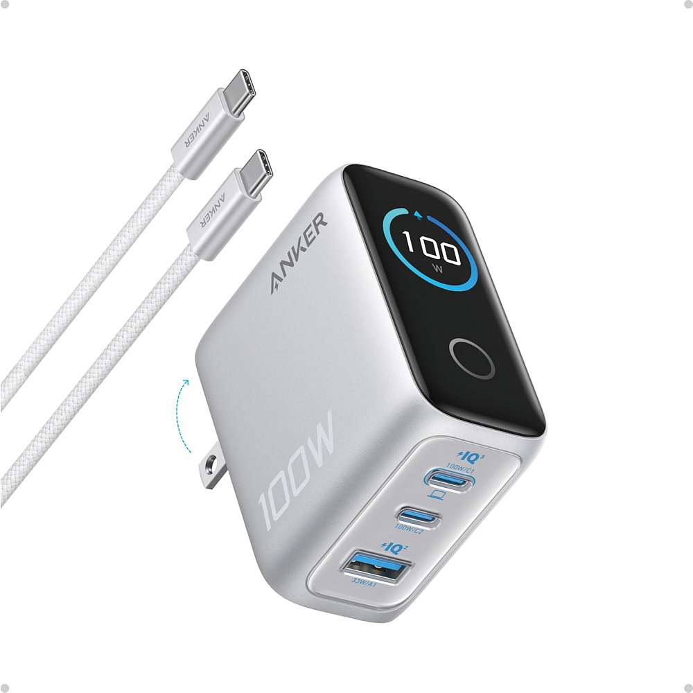 תמונה של מטען Anker 100W עם תצוגה חכמה בצבע כסוף. בחזית המטען מופיע מסך דיגיטלי המציג את עוצמת הטעינה בזמן אמת (100W). המטען כולל 3 יציאות טעינה – שתי יציאות USB-C ויציאת USB-A, ולצדו מוצג כבל USB-C ל-USB-C בצבע לבן. העיצוב קומפקטי עם תקע מתקפל לנשיאה נוח